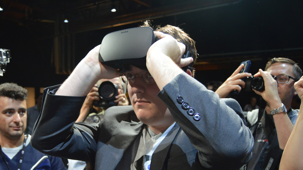 Palmer Luckey slipping on the Oculus Rift, before taking off his glasses. 