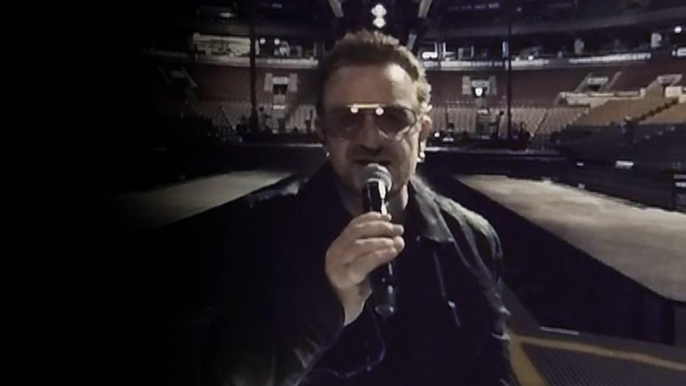 Bono fades in during the performance of "Song for Someone"