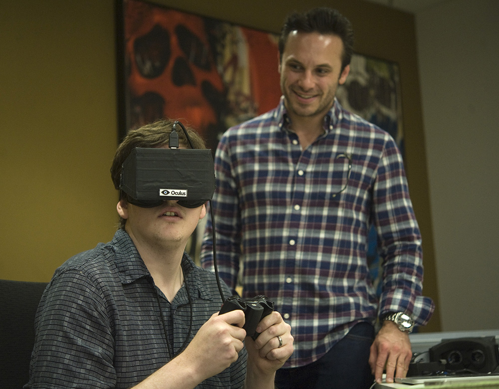 Ian Hamilton experiences the Oculus VR virtual reality head gear at the company's Irvine office with the help of CEO Brendan Iribe.
