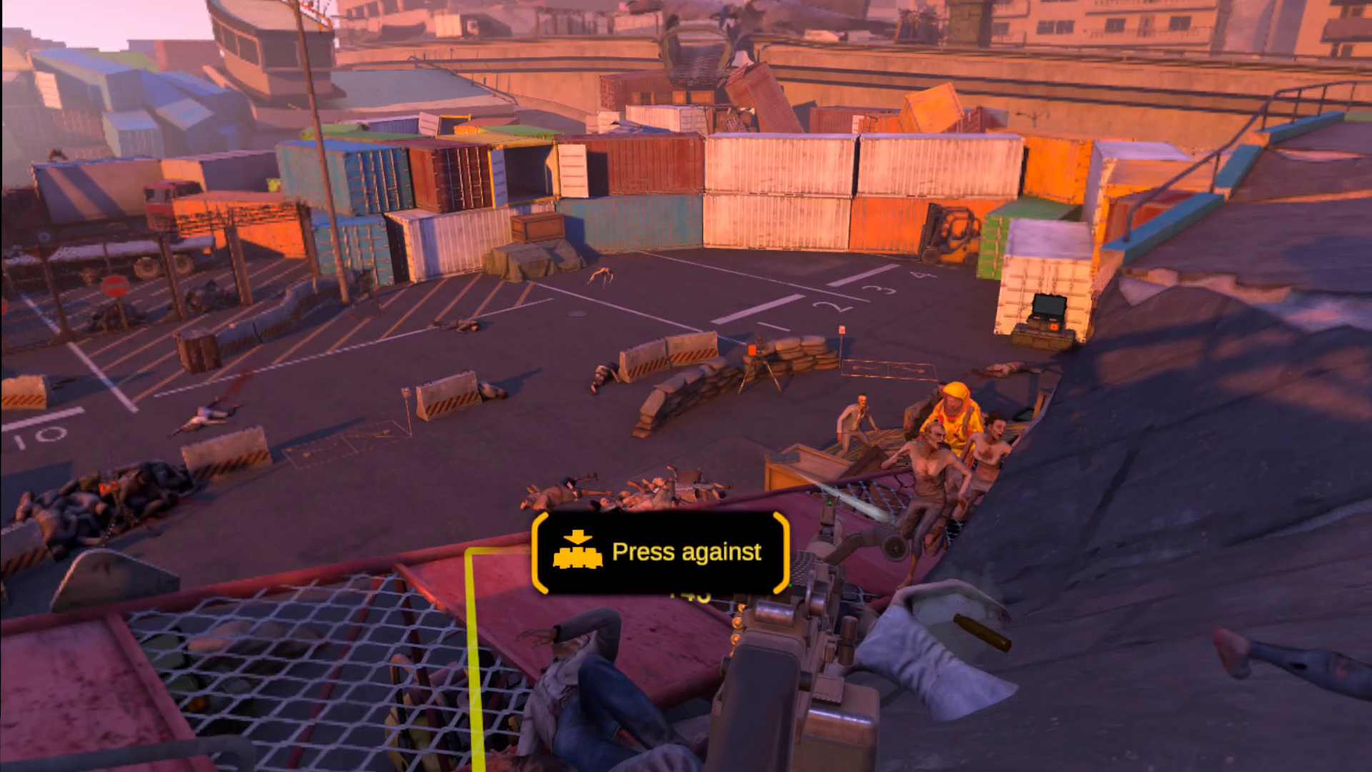 The player holds an LMG at the ready as a horde of undead climb up a ramp. There is a screen prompt for the player to reload by pressing their controller against their virtual ammo packs.